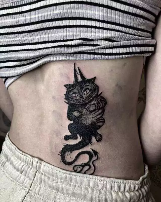 dark-themed cheshire cat tattoo on back