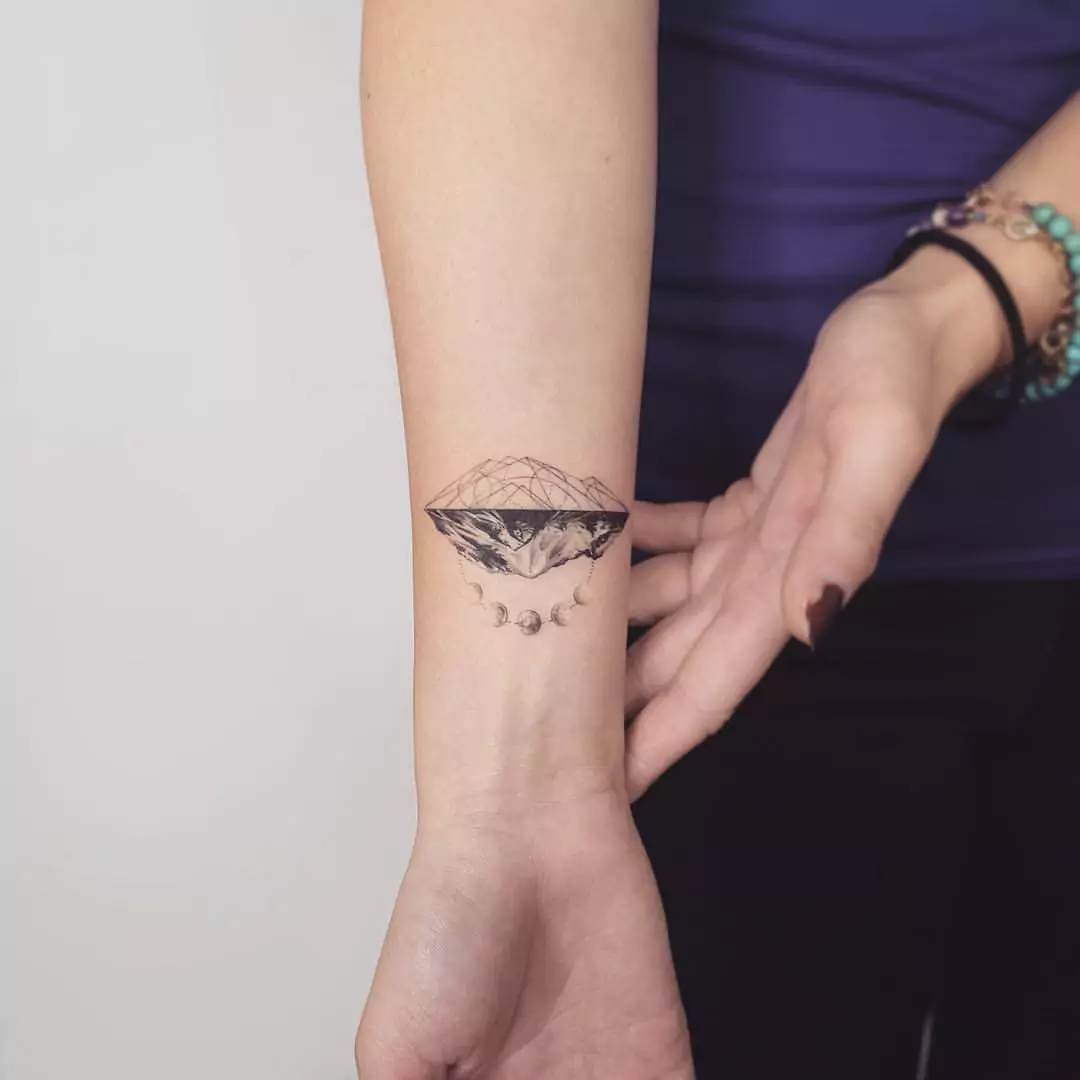 creative mountain and moon phases hand tattoo