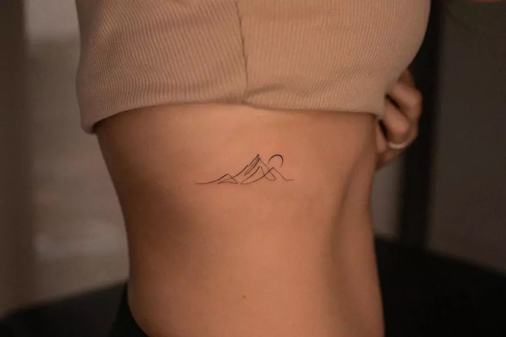 line art mountain tattoo on the rib