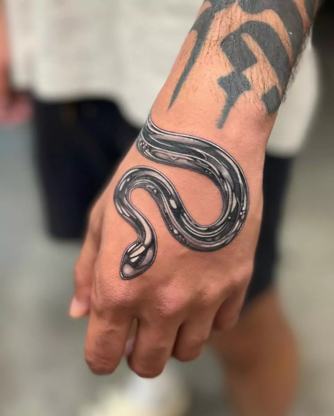 chrome style snake hand tattoo