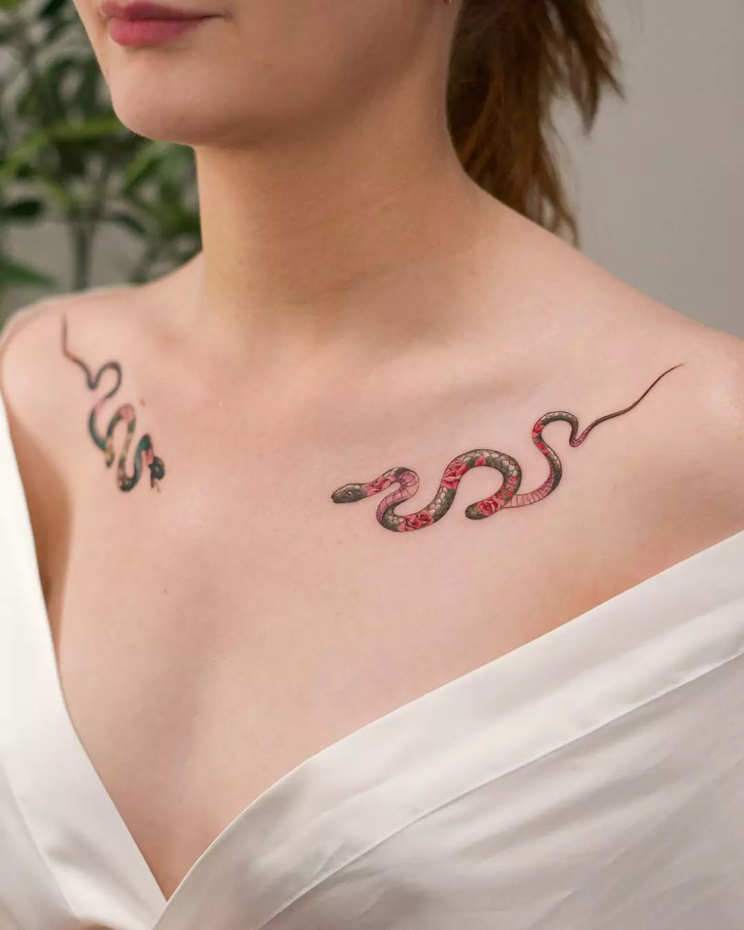 two small snake tattoos on the collarbone