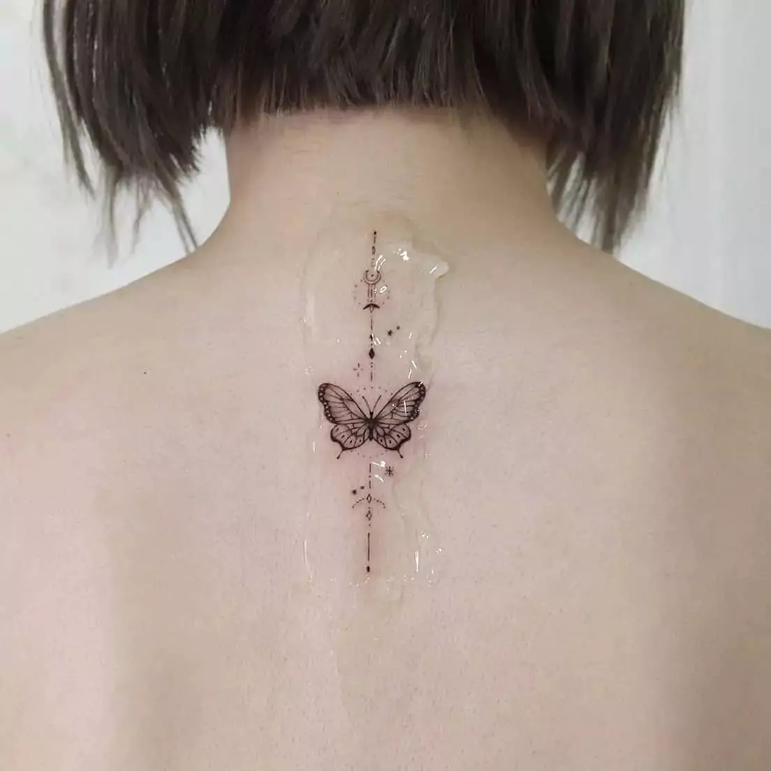 small ornamental butterfly nape tattoo